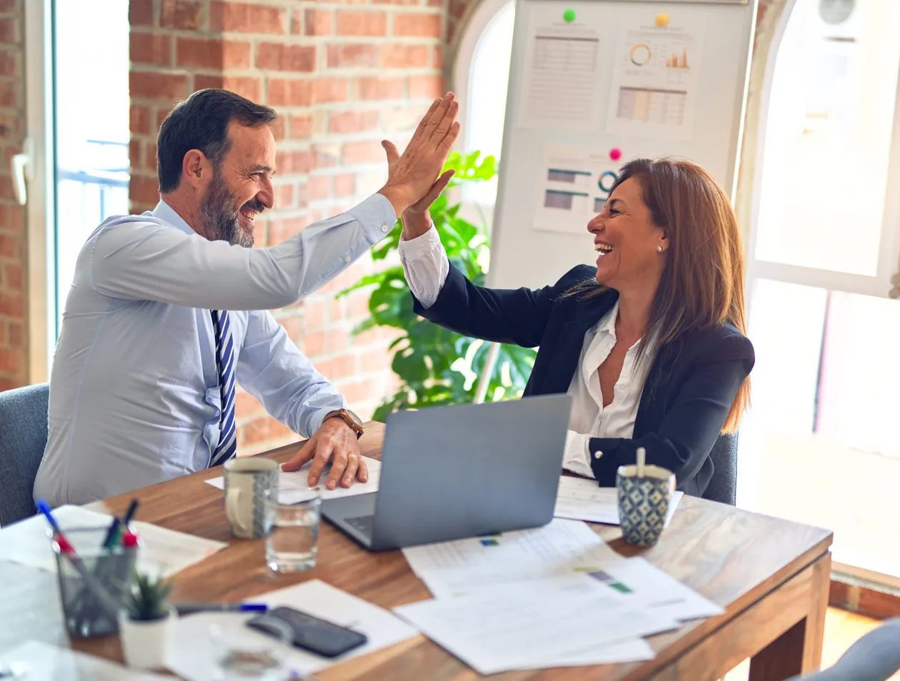 Two people high-fiving over a computer